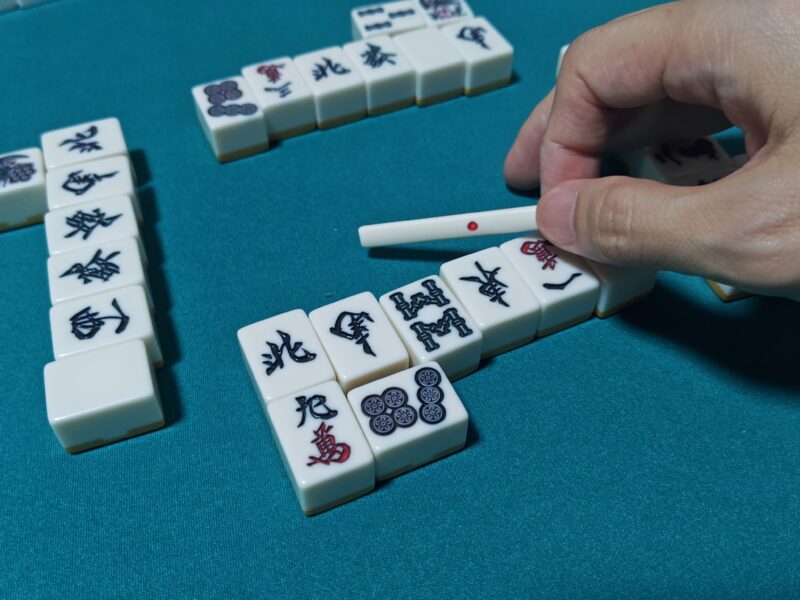 麻雀の対局後に卓上のリーチ棒を置く様子